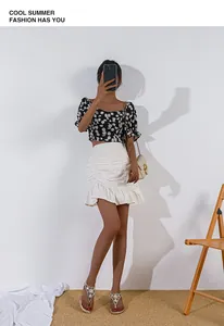 Dettaglio del crop top floreale con maniche a sbuffo con minigonna a ruche e sandali di perle