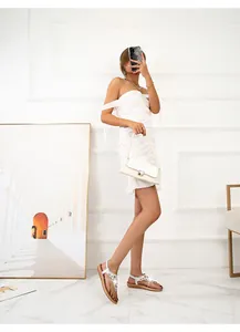 Flache Sandalen mit Strasssteinen am Modell in einem minimalistisch weißen Interieur