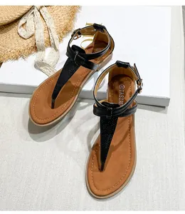 Detailed top view of black T-strap flat sandals with snake texture and golden buckle