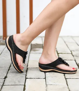 Détail de sandales compensées noires pour femmes avec fleurs et découpes laser