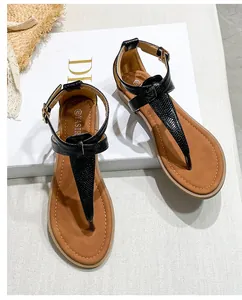 Detail of flat T-strap sandals with snake print texture and adjustable ankle buckle