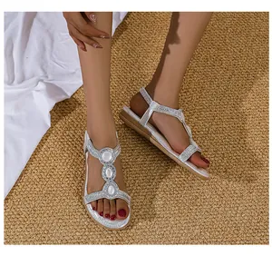 Detailaufnahme silberner T-Riemen-Sandalen mit funkelnden Strasssteinen und weißen Perlen