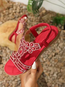 Detailed view of red sandals with floral rhinestone patterns and quilted sole