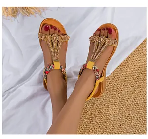 Detail von gelben T-Riemen-Sandalen im Boho-Stil mit verzierten Metallteilen