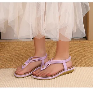 Détail de sandales plates tressées violet clair avec boucle en métal doré chic