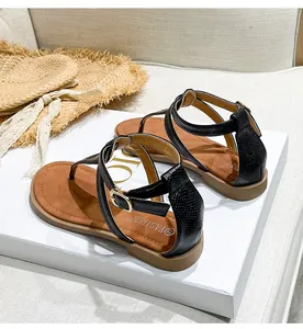 Detail of black faux leather flat sandals with T-strap and adjustable ankle strap design