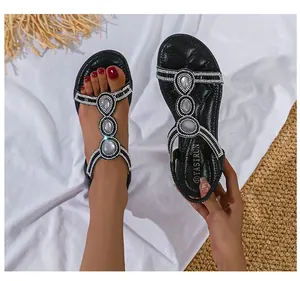 Details schwarzer Boho-Sandalen mit T-Riemen, weißen Strasssteinen und Perlenbesatz