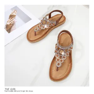 Nahaufnahme von flachen Sandalen im Boho-Stil mit funkelnden Straßsteinen und Perlenblumen
