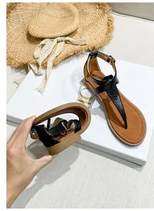 Detail of ultra-soft flexible sole on black T-strap sandals with snake skin texture
