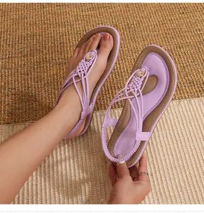 Détail de sandales tressées violettes avec boucles dorées sur un tapis de paille
