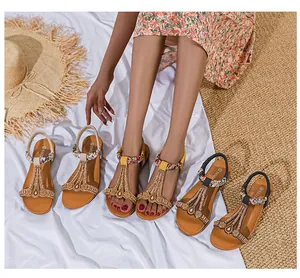 Detail von flachen Bohemian-Sandalen mit geflochtenen T-Riemen und bunten Perlenverzierungen