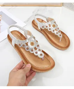 Detail der flexiblen Sohle und der glitzernden Strassblume dieser silbernen Sandalen