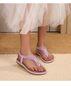 Détail de sandales bohèmes violettes avec brides tressées et décoration fleur dorée