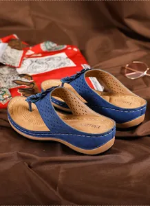 Détail de sandales compensées bleu marine avec décor floral et motifs découpés au laser