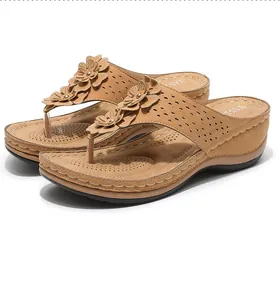Détail de sandales compensées chameau avec fleurs en cuir et motifs découpés au laser