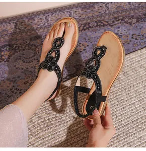 Détail de sandales plates pour femmes avec strass brillants et semelle aspect bois
