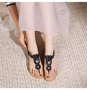 Vue de dessus de sandales plates T-strap noires bohèmes avec strass et perles portées