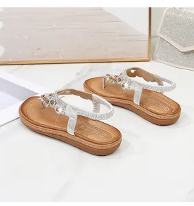 Detail von silbernen Boho-Sandalen mit funkelnden Strassblumen und elastischem Fersenriemen
