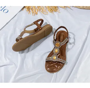 Detaillierte Nahaufnahme brauner flacher Sandalen mit glitzernden Strasssteinen und Perlen