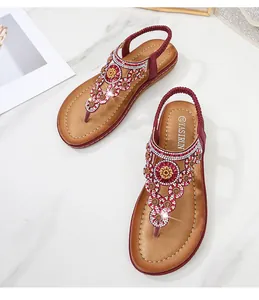 Detail von weinroten Boho-Flachsandalen mit funkelnden Strasssteinen und Blumenmuster