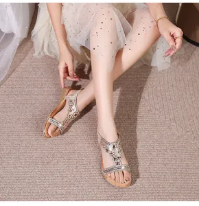 Close-up of champagne gold flat sandals with bohemian rhinestone flower detailing