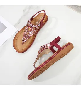 Detailansicht der Boho-Sandalen mit tiefroten Riemen und floralen Strasssteinen-Verzierung