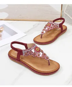 Details roter Bohemian-Sandalen mit Blumenstickerei und funkelnden Strasssteinen
