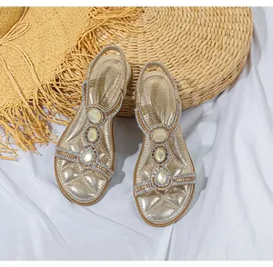 Nahaufnahme goldener flacher Sandalen mit funkelnden Strasssteinen und Perlmutt-Ornamenten