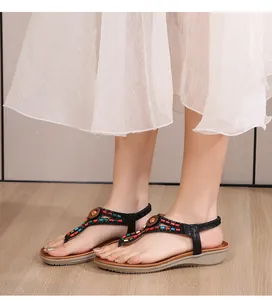 Détail de sandales plates bohèmes avec des perles colorées et une sangle en T avec bois