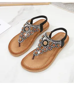 Detail einer Boho-Flachsandalette mit kunstvoller Strassblume und Perlenapplikation