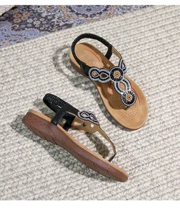 Detailansicht der flachen Boho-Sandalen mit Strasssteinen und Blumenapplikationen