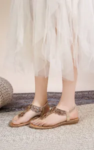 Dettaglio di sandali boho color oro champagne con decoro floreale in strass e elastico