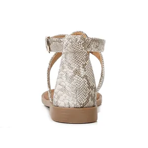 Rear view of women's flat sandals featuring beige snakeskin pattern and ankle straps