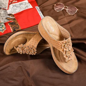 Détails de sandales compensées marron avec motifs découpés au laser et fleurs en cuir