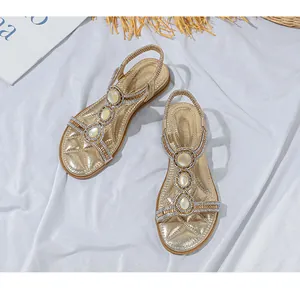 Detailansicht goldener flacher Sandalen mit T-Riemen, Perlen und Perlen für Sommerurlaube