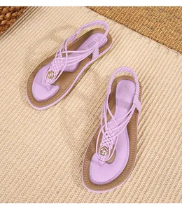Détail de sandales bohèmes violettes à lanières tressées et ornements métalliques dorés