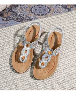 Detail of wedge sandals featuring rhinestone T-straps and yellow floral embellishments