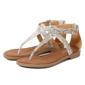 Detail view of women's T-strap flat sandals featuring snake skin pattern and buckle closure