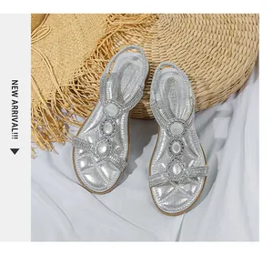 Draufsicht auf silberne flache Sandalen mit Strass und Edelsteinen auf weißer Seide