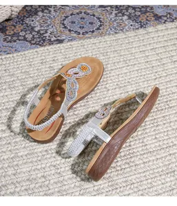 Detail of wedge sandals with rhinestone straps, orange flower accent and anti-slip sole