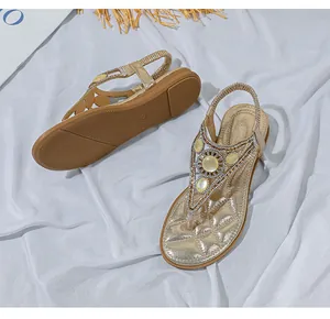 Dettaglio di sandali bassi bohémien con cinturini dorati e ornamento in pietra gialla
