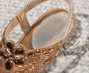 Dettaglio di sandali dorati con strass, soletta imbottita in PU e decorazioni di gemme
