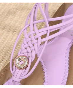 Détail des lanières tressées de sandales bohèmes violettes avec boucle en métal doré