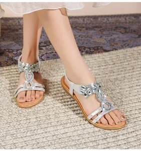 Detailaufnahme silberner Boho-Sandalen mit aufwendigen Blumenmustern aus Strasssteinen
