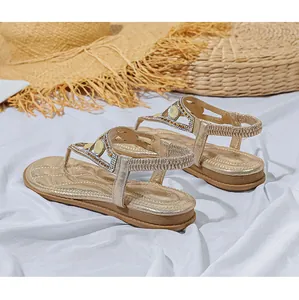Dettaglio dei sandali bohémien color oro con strass lucidi e cinturino elastico posteriore