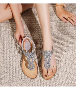 Gros plan de sandales bohèmes avec strass et motif floral portées par un mannequin