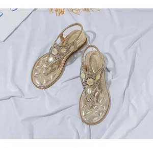 Dettaglio di sandali bassi dorati boho con grande gemma gialla e strass scintillanti