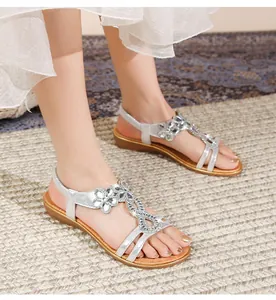 Detail silberner Boho-Flach-Sandalen mit funkelnden Kristall-Strassblumen-Details