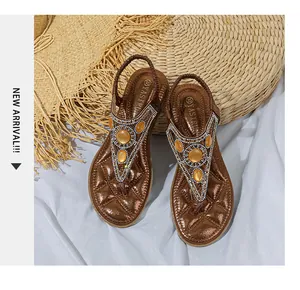 Dettaglio di sandali boho con strass scintillanti e gemme arancioni su cinturini marroni