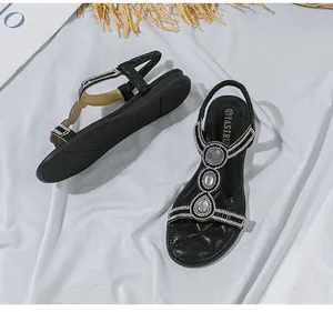 Detail von schwarzen flachen Bohemian-Sandalen mit Tropfen-Strasssteinen und Gummiband